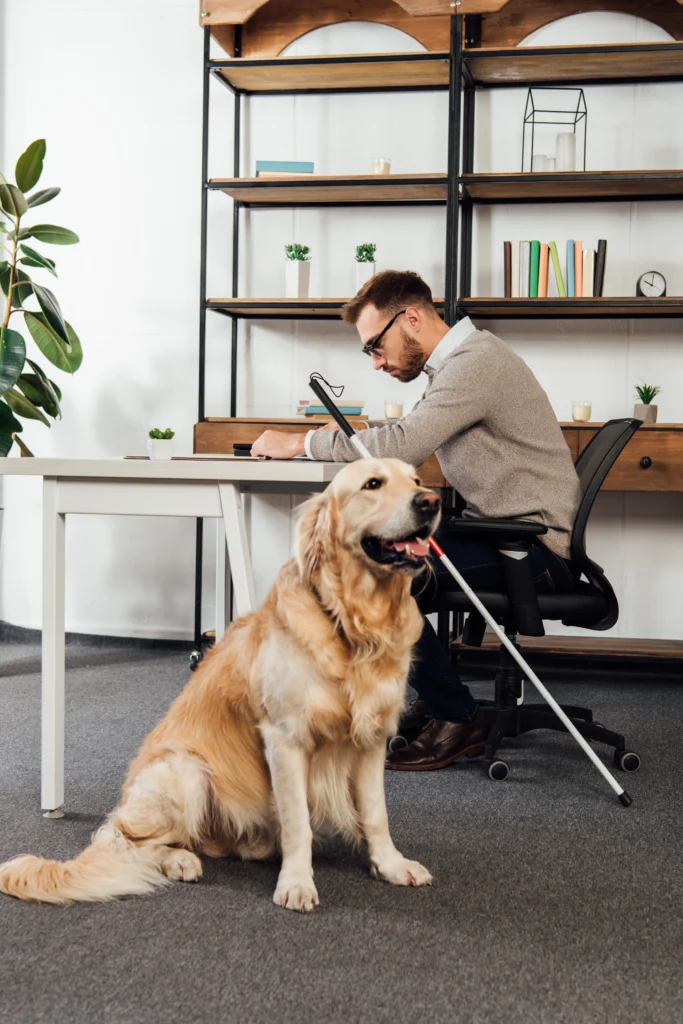 blind-man-reading-at-table-beside-golden-retriever