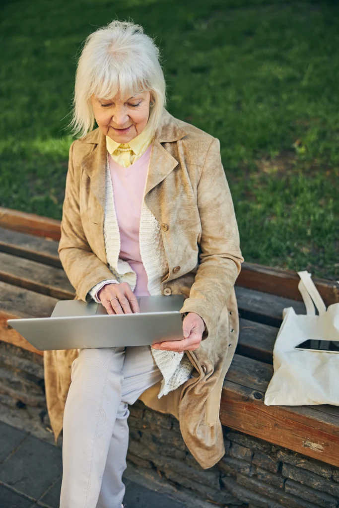 Ältere Dame verendet Laptop im Park